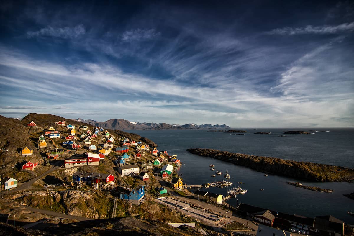 aerial view of the colorful houses and rugged coastline of kangaamiut village in greenland surrounded by dramatic arctic landscapes and sea