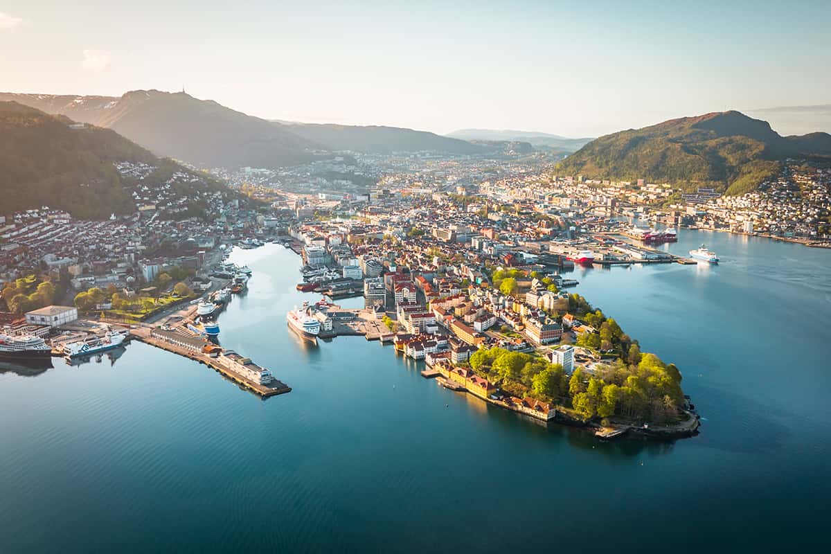 A scenic view of Bergen, Norway, with colorful wooden houses along the waterfront, surrounded by mountains and fjords