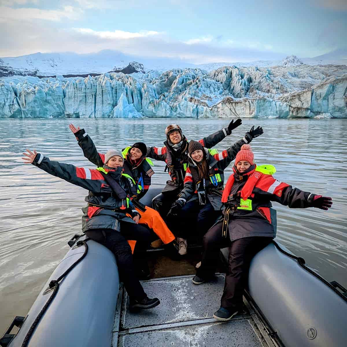 A Zodiac boat floating on the icy waters of Fjallsárlón glacier lagoon in Iceland, surrounded by icebergs and views of the glacier tongue in the background