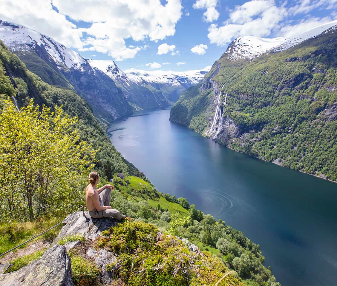 Deep blue fjord winding between steep cliffs and lush green mountains in Geirangerfjord, Norway