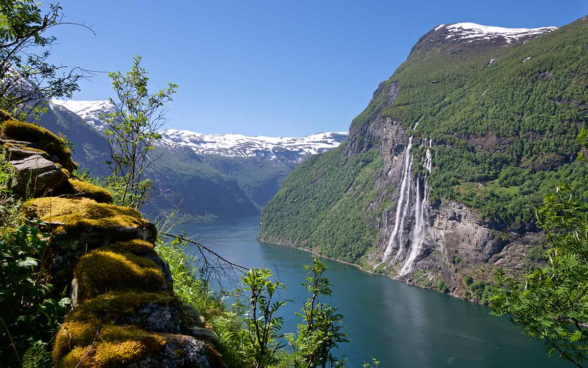 Deep blue fjord winding between steep cliffs and lush green mountains in Geirangerfjord, Norway