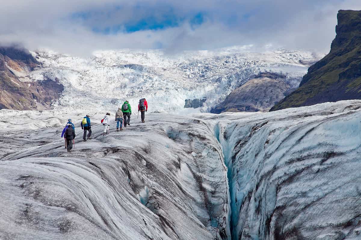 A glacier in Iceland with deep blue ice, crevasses, and rugged icy terrain under a cloudy sky