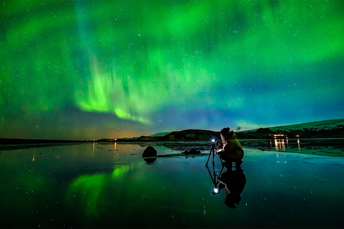 Northern lights dancing across the night sky in Iceland, with vibrant green and purple auroras over a peaceful landscape