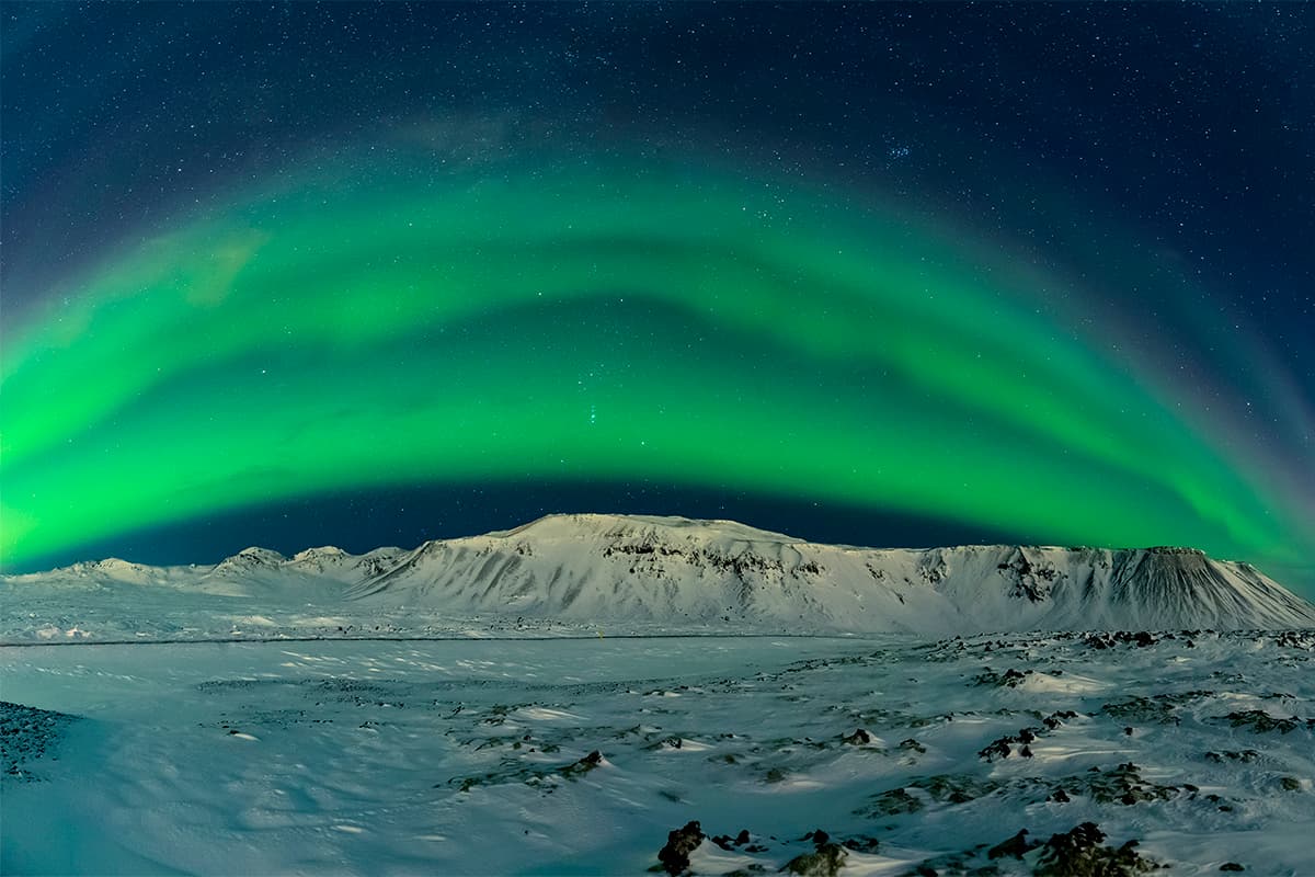 Northern lights dancing across the night sky in Iceland, with vibrant green and purple auroras over a peaceful landscape