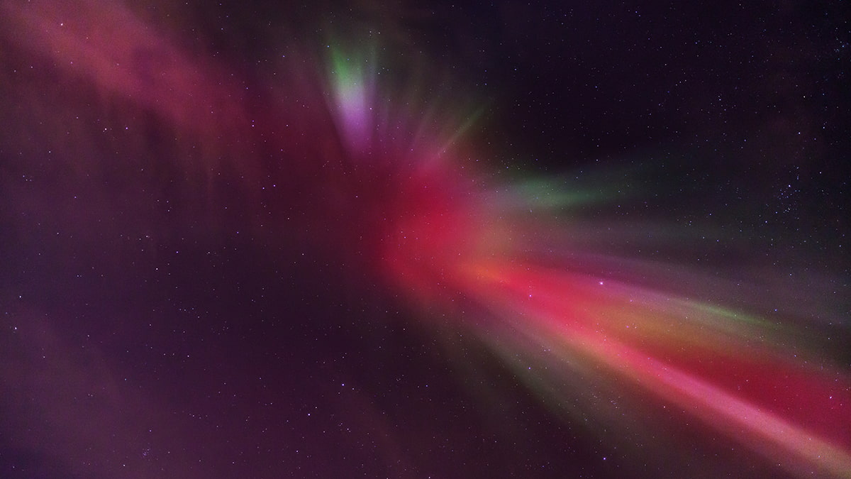 Northern lights dancing across the night sky in Iceland, with vibrant green and purple auroras over a peaceful landscape