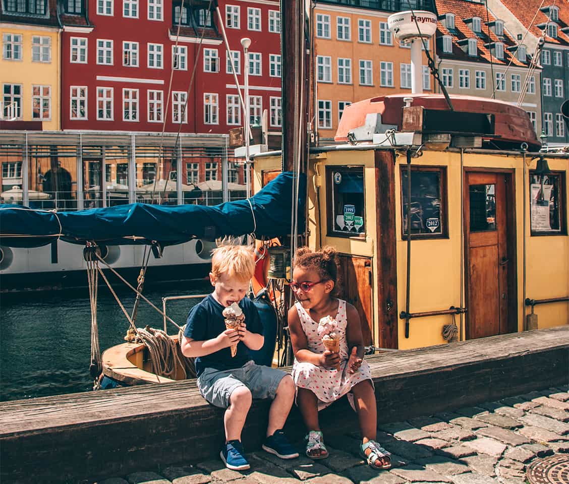 Nyhavn canal in Copenhagen, Denmark, lined with colorful buildings and docked boats on a sunny day