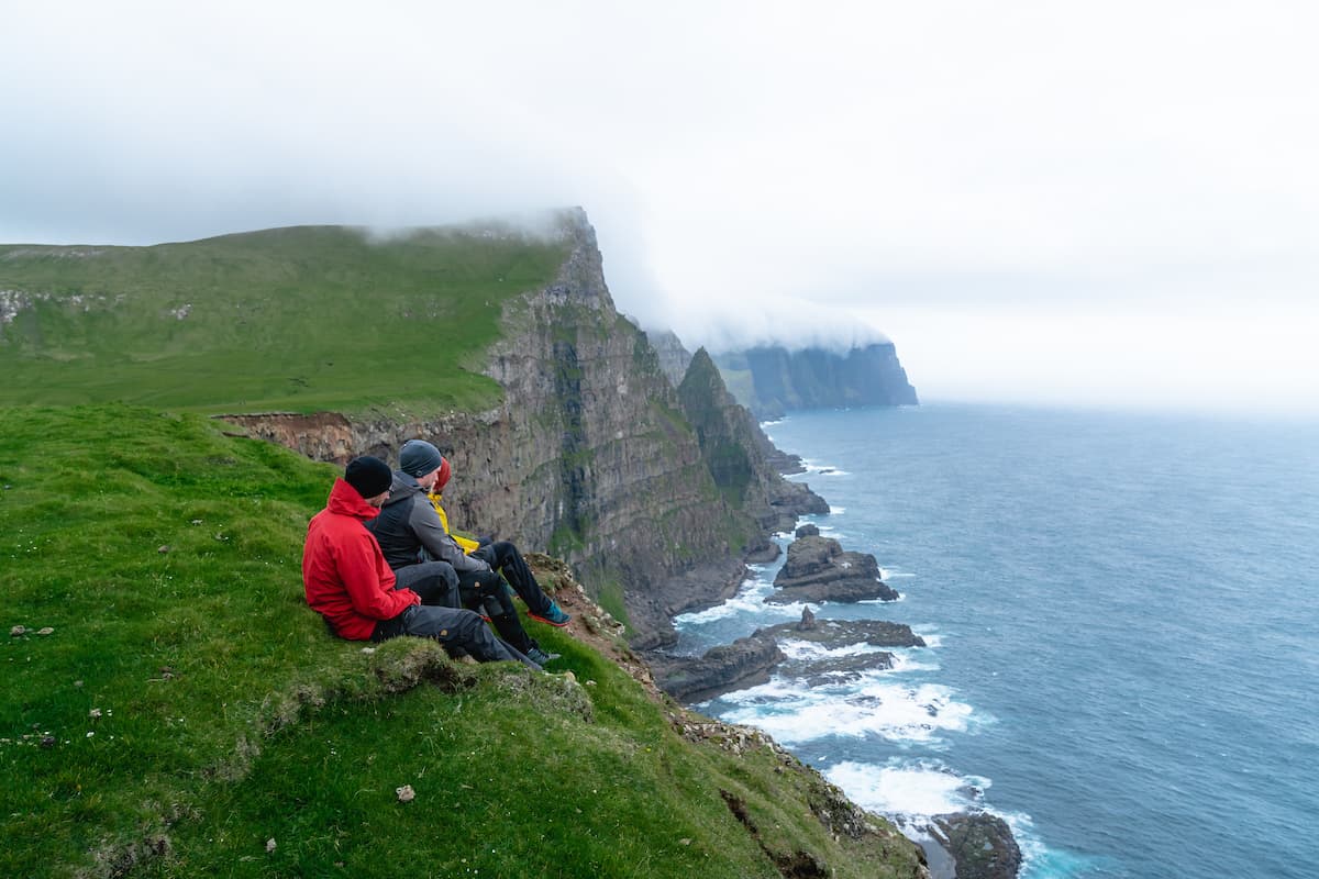 People sitting near cliffs in Faroe Islands