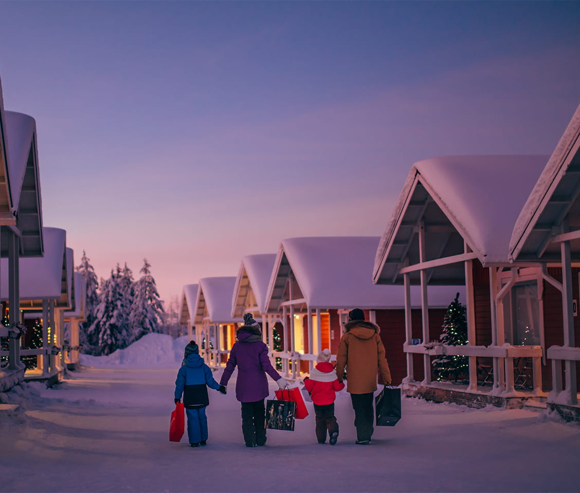 Santa Claus Village in Rovaniemi, Finland, with snowy log cabins, festive lights, and the Arctic Circle line
