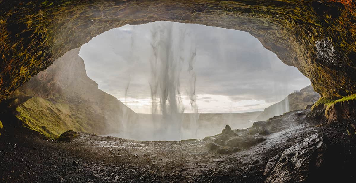 Seljalandsfoss waterfall in South Iceland cascading over a high cliff with a walking path behind the falling water