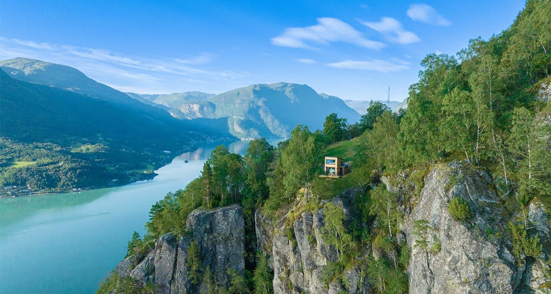 Sognefjord stretching between steep mountains in Norway, with calm fjord waters and dramatic natural scenery under a partly cloudy sky