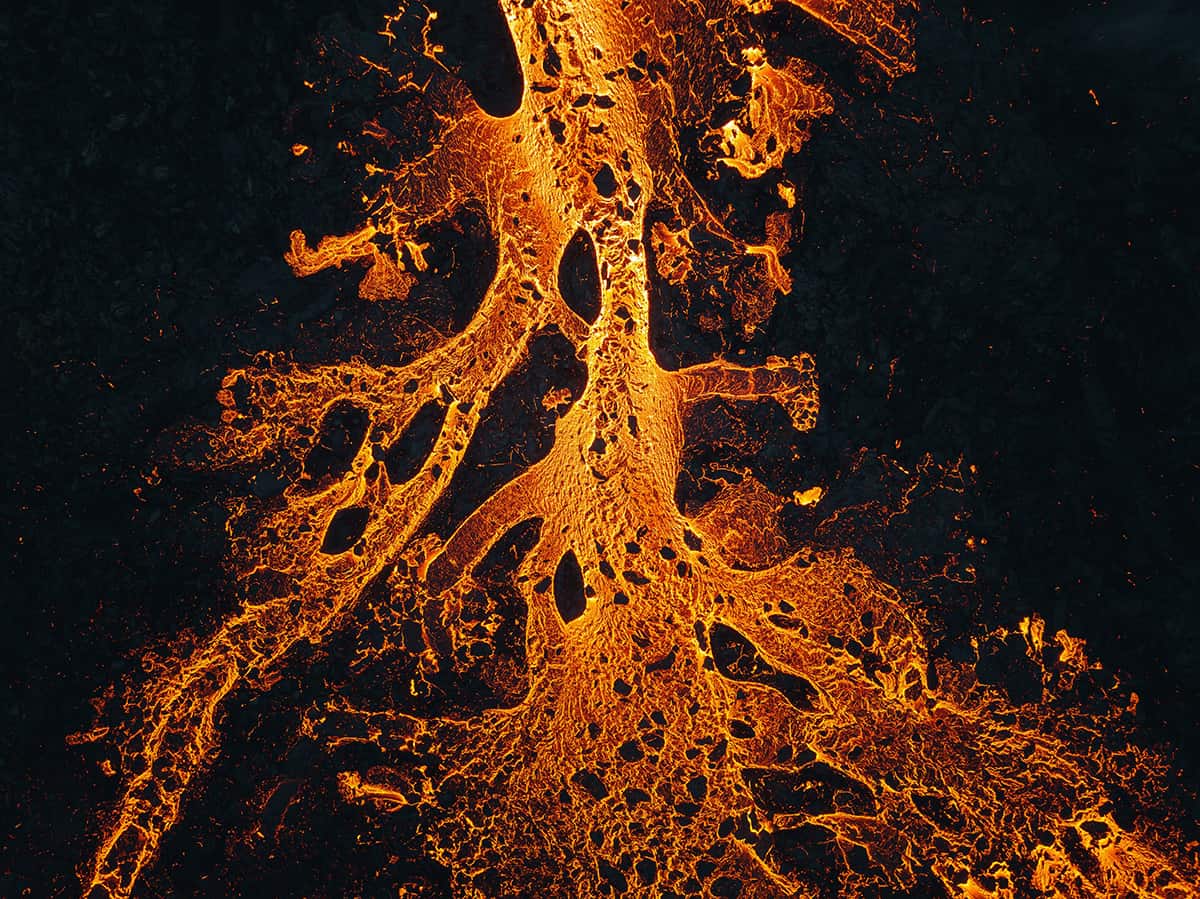 A volcanic eruption in Iceland with glowing lava fountains, thick smoke, and molten rock flowing across a dark volcanic landscape