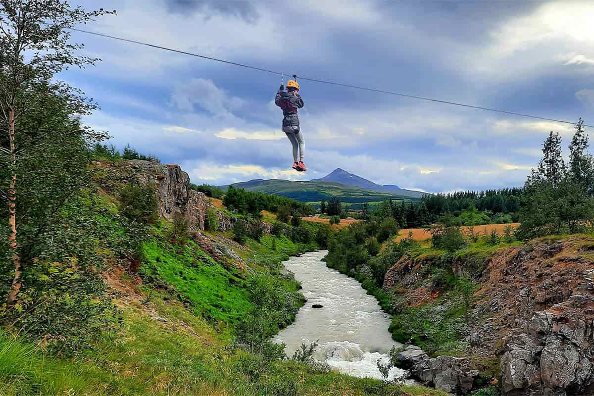 Adventurer ziplining over a dramatic Icelandic canyon, surrounded by rugged nature