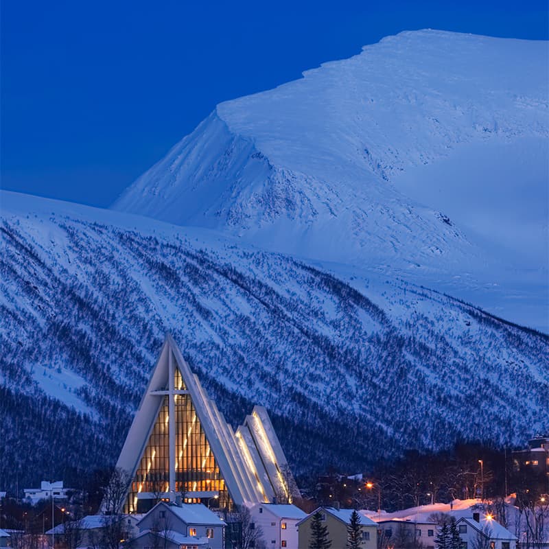Modern white Arctic Cathedral rising against a clear sky in Tromsø with sharp lines and dramatic arctic surroundings