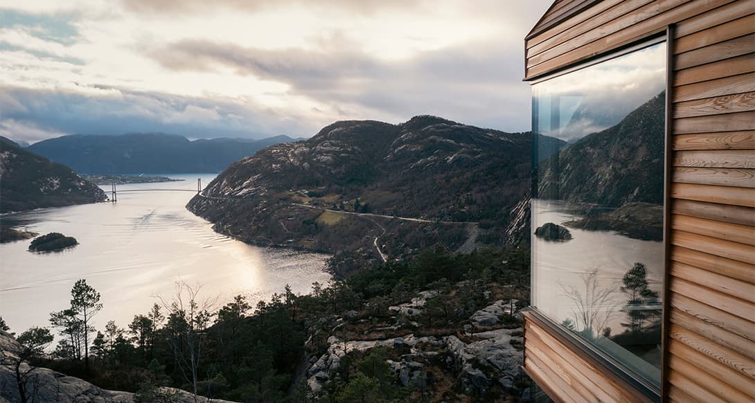 Steep mountain slopes rise above a calm fjord in Western Norway reflecting the rugged beauty of Scandinavian nature and adventure