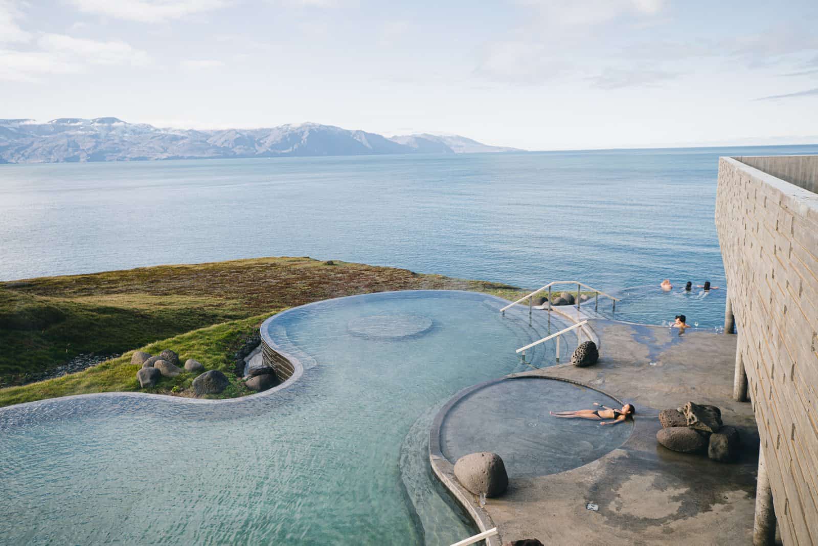 People relaxing in warm geothermal sea baths overlooking the ocean at Geosea in Husavik Iceland with a soothing and scenic atmosphere
