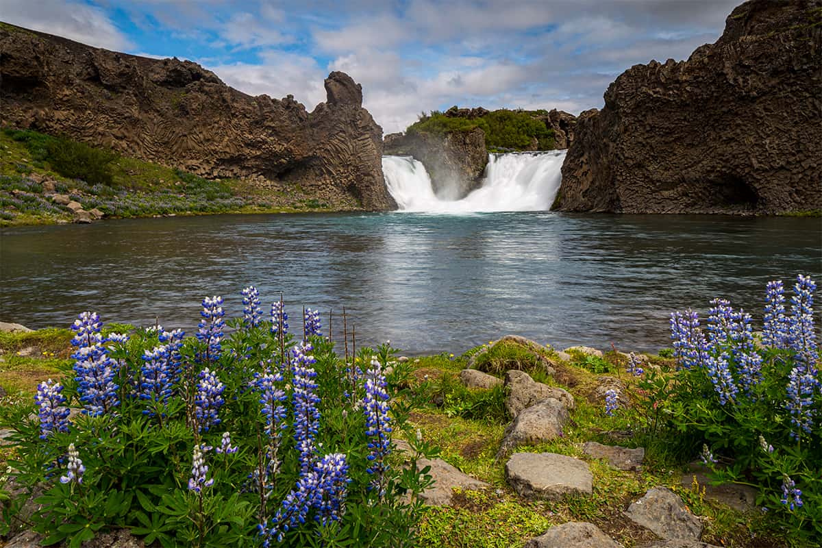 Twin waterfalls flowing into a serene pool surrounded by lava rocks at Hjalparfoss in South Iceland with a peaceful natural vibe