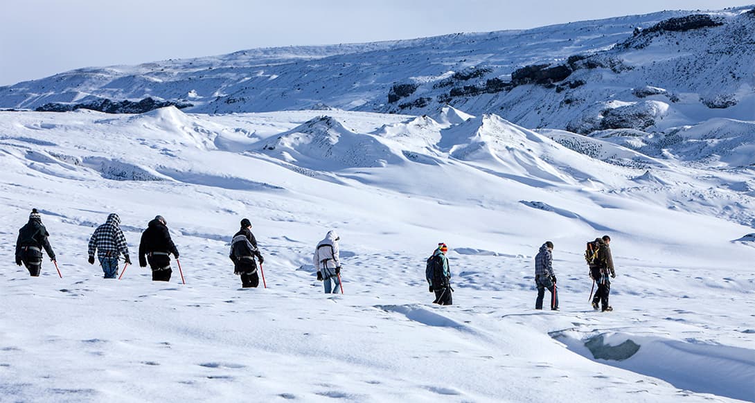 Ice walk on a glacier in Iceland with hikers crossing frozen terrain in safety gear, surrounded by dramatic ice formations and Arctic scenery