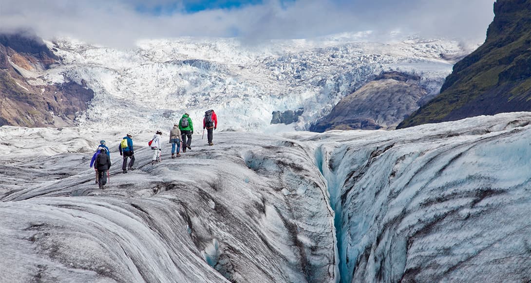 Walking on a glacier in Iceland with crampons and safety gear, exploring icy landscapes and crevasses in a guided arctic adventure