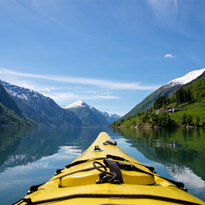 Kayaking on calm waters in Fjærlandsfjord, Norway, surrounded by steep mountains and serene fjord landscapes in a peaceful adventure setting