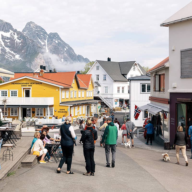 Street scene in Henningsvær, Norway, with locals and visitors enjoying the vibrant atmosphere of this coastal village in the Lofoten Islands