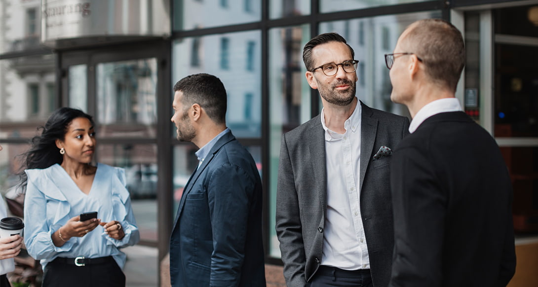 Group of people engaged in conversation during a MICE meeting outside a modern building in Iceland highlighting professional networking