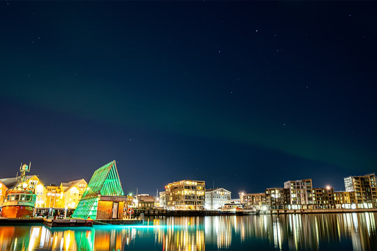 vibrant northern lights dancing above Tromso in Norway with glowing green skies creating a magical and peaceful arctic night scene