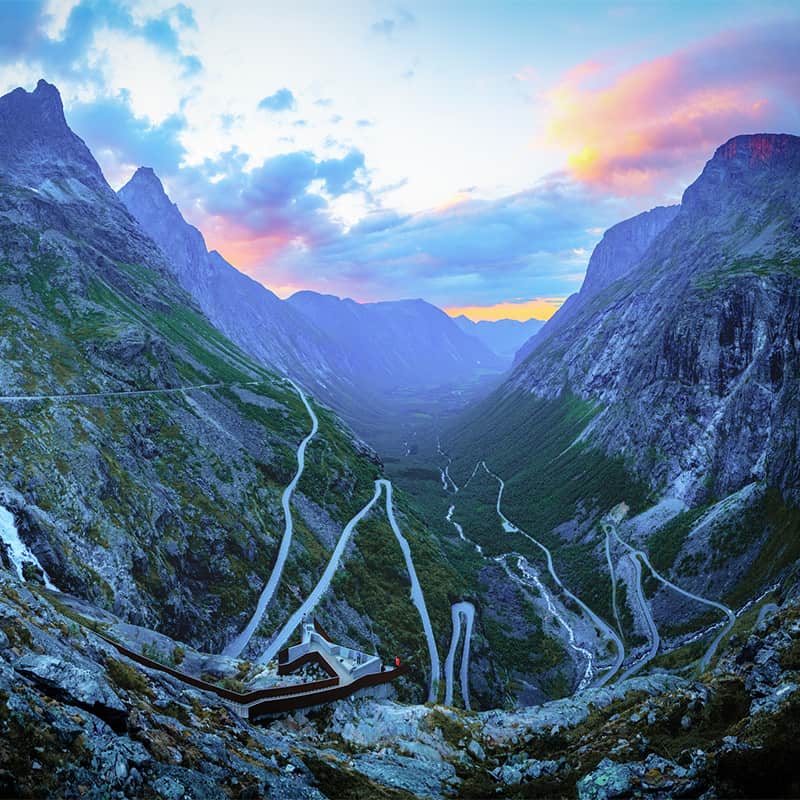 Trollstigen Road in Norway winding through steep mountain terrain with dramatic switchbacks and lush scenery on a famous scenic driving route