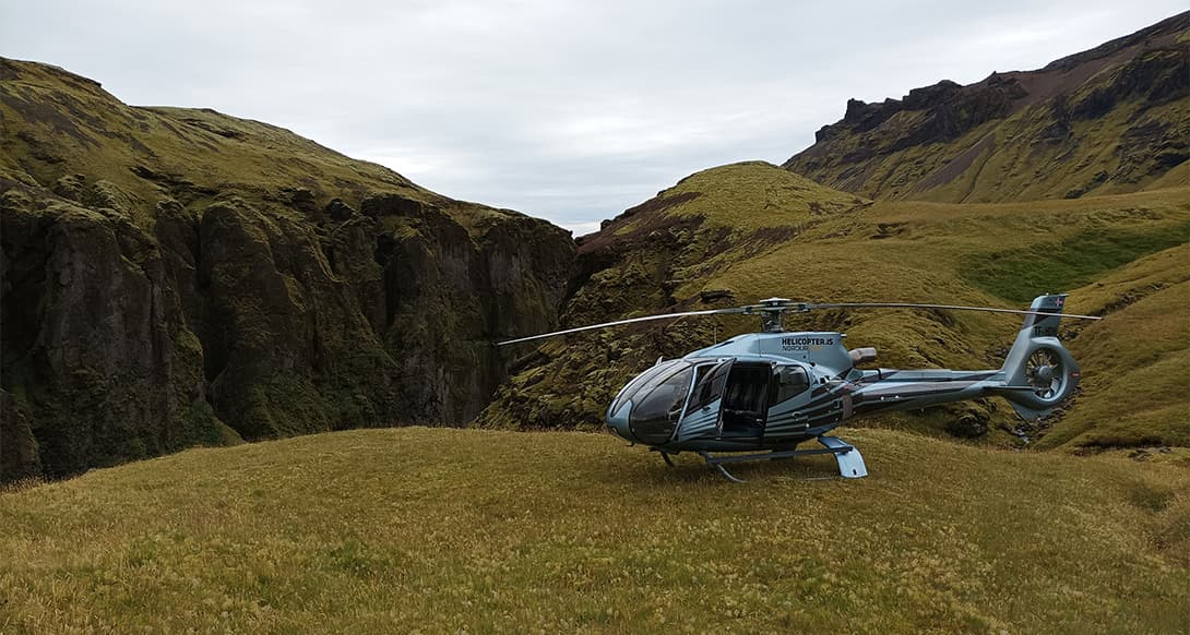 Helicopter landing on a remote Icelandic plateau with dramatic volcanic terrain and sweeping views of untouched highlands and rugged nature