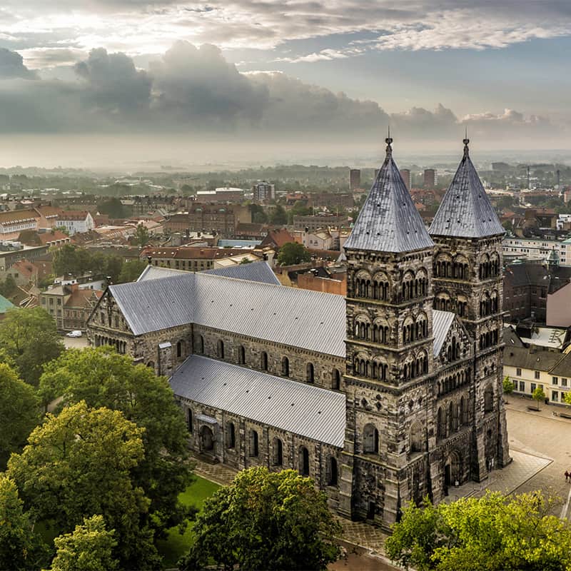 Lund Cathedral in Sweden with twin towers and Romanesque stone architecture viewed from the front in a historic city center with overcast sky