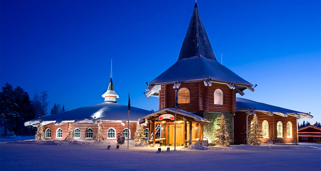Snow covered Santa Claus Village in Rovaniemi Finland with festive wooden buildings twinkling lights and magical winter atmosphere in Lapland