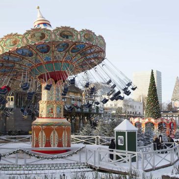 Tivoli Gardens in Copenhagen covered in snow with festive Christmas lights decorated trees and cozy winter charm in a magical holiday setting